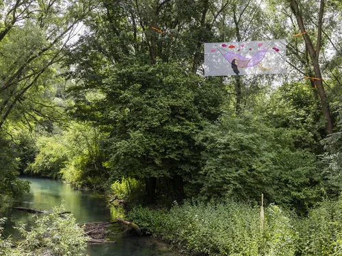A banner stretched between the trees depicts a female figure lying in a hammock.