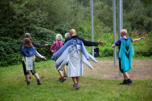 Die Performer und Performerinnen der Performance Gruppe Flusswärts tanzen vor dem Kunstwerk von raumlaborberlin.
